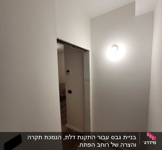 מסדרון עם דלת פתוחה ותאורה על הקיר